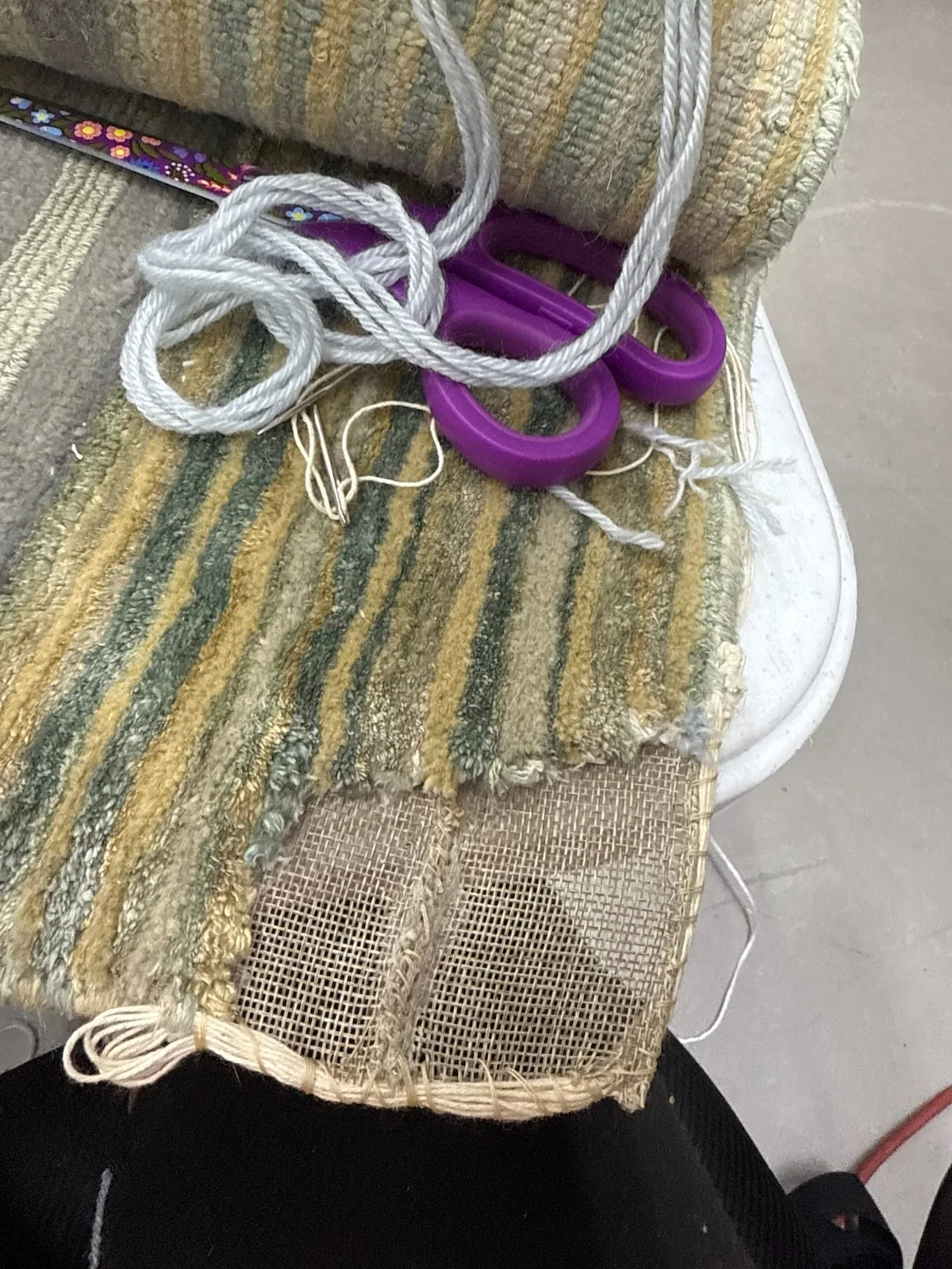 A worn rug edge part-way through overcasting by hand, photographed at our plant for Boca Raton